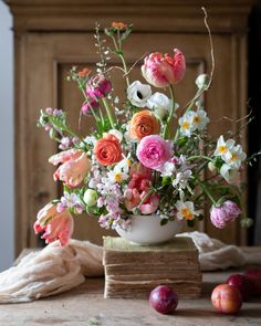 a vase filled with lots of flowers sitting on top of a table next to books