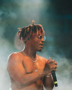 a man with dreadlocks holding a microphone in his right hand while standing on stage