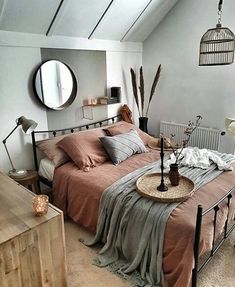 a bed room with a neatly made bed and a round mirror on the wall above it