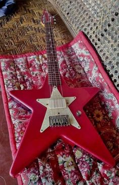 a red guitar sitting on top of a bed