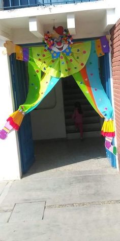 a colorful clown costume hanging from the side of a building with stairs leading up to it