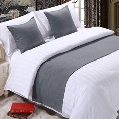 a bed with white and grey sheets in a bedroom