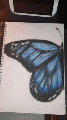 a drawing of a blue butterfly sitting on top of a piece of paper