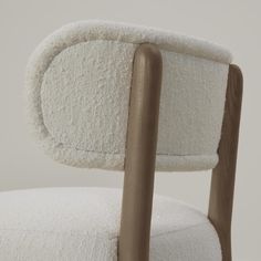 a white chair with a wooden armrest and seat cushion on top of the back