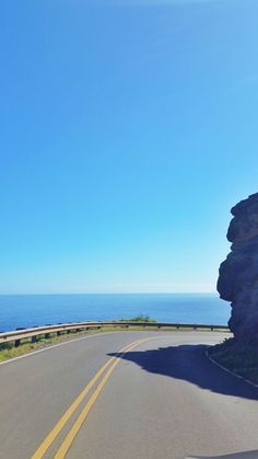 an empty road near the ocean on a sunny day