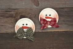 two snowmen made out of paper plates sitting on top of a wooden table