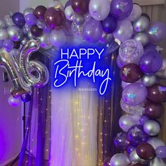 a purple and silver balloon arch with the words happy birthday written in white on it