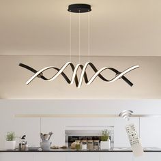 a modern kitchen with white cabinets and black counter tops is illuminated by an elegant chandelier that hangs from the ceiling