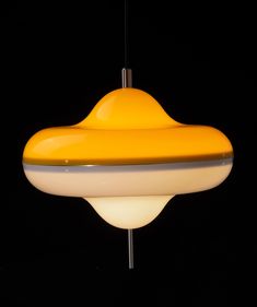 a yellow and white light hanging from a ceiling fixture in a dark room with black background