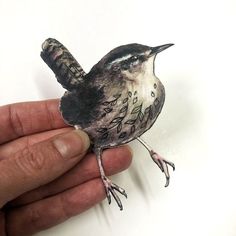 a hand is holding a small bird that has been painted on it's body