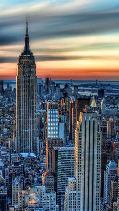 the empire building in new york city, ny at sunset with clouds moving over it