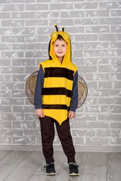 a young boy wearing a bee costume standing in front of a brick wall with his hands on his hips