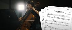 an image of a woman playing cello in the dark with sheet music next to her