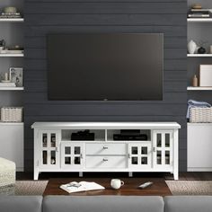 a large flat screen tv mounted to the side of a white entertainment center in a living room