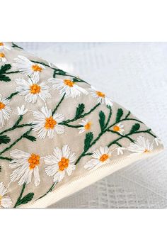 a pillow with daisies and leaves on it