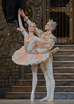 two ballerinas dressed in white and gold are performing on stage