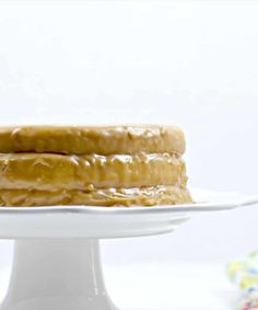 a three layer cake sitting on top of a white cake platter with frosting