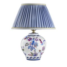 a blue and white vase with a lamp on it's side next to a light