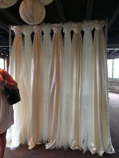 a woman standing in front of some white curtains