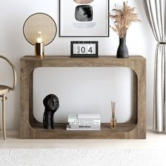 a table with some books and vases on it in front of a white wall