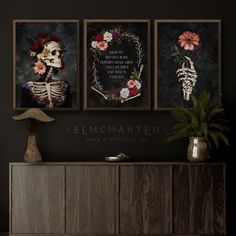 three framed art prints on the wall above a dresser in a dark room with flowers and skeleton decorations