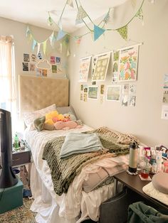 a messy bedroom with clothes hanging from the ceiling and pictures on the wall above the bed