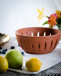 a brown bowl sitting on top of a table next to lemons