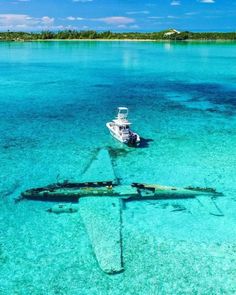 a boat floating on top of a blue ocean next to an airplane in the water