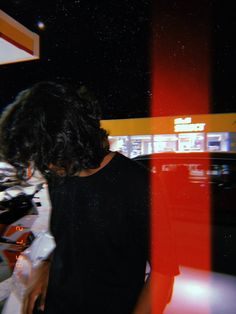 a man standing in front of a red and yellow sign at night time with his head down