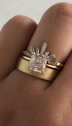 a person's hand with a gold ring on it and a pink diamond in the middle