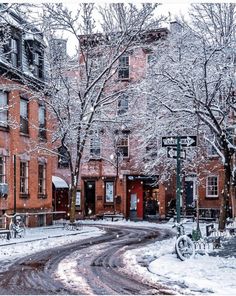 a snow covered street with buildings and bicycles parked on the sidewalk in front of it