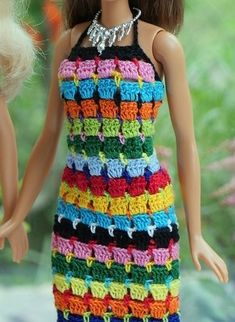 a doll is wearing a multicolored crocheted dress