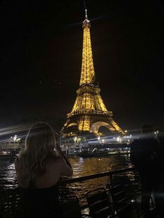 the eiffel tower lit up at night with people looking on from across the river