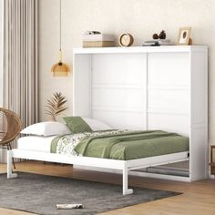 a white bed sitting next to a window on top of a hard wood floored floor