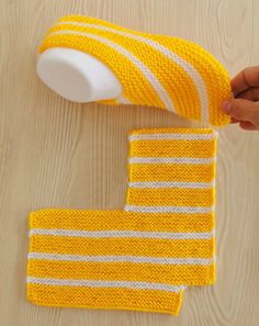 someone is holding a roll of yellow and white knitted washcloth on a wooden surface