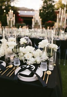 the table is set with white flowers and black napkins