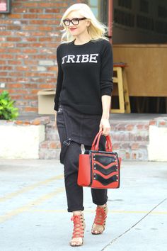 a blonde woman carrying a red handbag while walking down the street