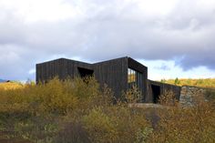 an abandoned building sits in the middle of a field with tall grass and yellow flowers