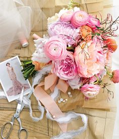 a bouquet of flowers sitting on top of a piece of paper next to scissors and pictures