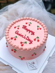 a pink birthday cake with cherries on it