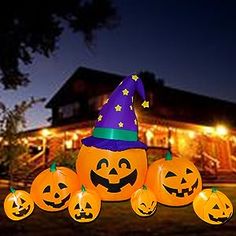 halloween pumpkins with witches hats on them in front of a house lit up at night