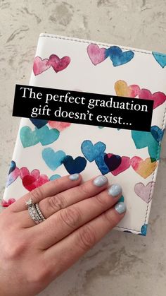 a woman's hand holding a book with hearts on it and the words, the perfect graduation gift doesn't exist