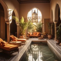 an indoor swimming pool with seating and potted plants in the center, surrounded by arched windows