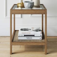 a table with books, vase and lamp on it in front of a white wall