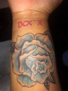 a close up of a person's wrist with a rose tattoo on it