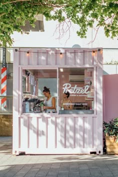 a woman standing behind a pink food stand