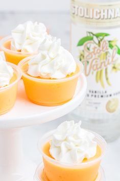 three dessert cups with whipped cream on top and a bottle of booze in the background