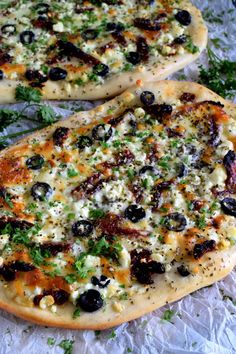 two pizzas with olives, cheese and herbs