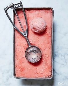 a scoop of ice cream next to a spoon on a pink tray with powdered sugar