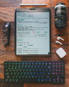 a tablet computer sitting on top of a wooden desk next to a keyboard and mouse